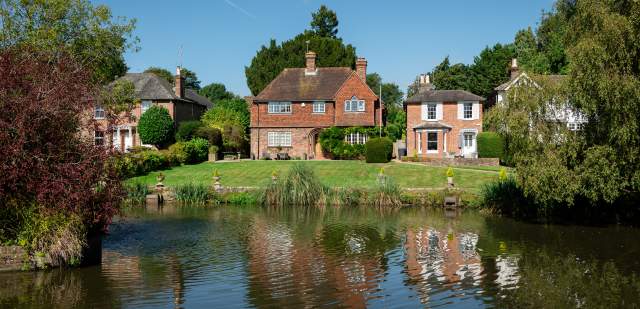 Three large red brick cottages set on the banks of a pond at Lindfield, Sussex