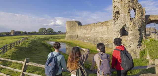Group look at the ruins of Pevensey Castle in 1066 country, Sussex