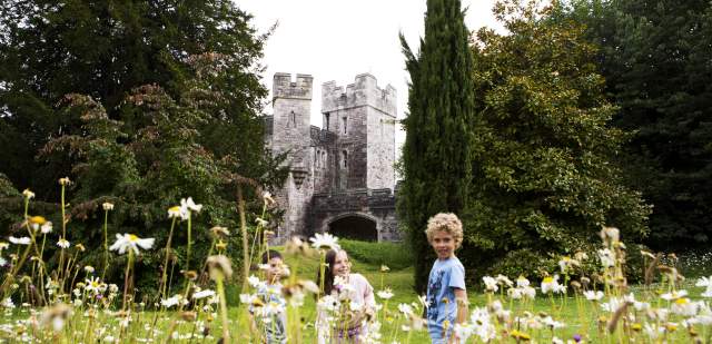 A group of children playing in a wildflower meadow with Lewes Castle in the background