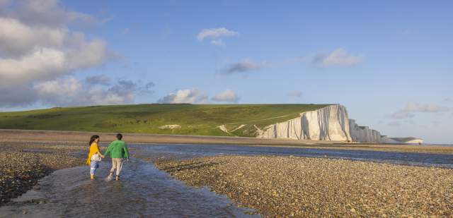 A couple walk in the water at low tide near Seven Sisters
