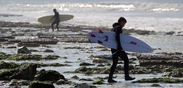 Two surfers on the rocky coastline at Birling Gap, Sussex