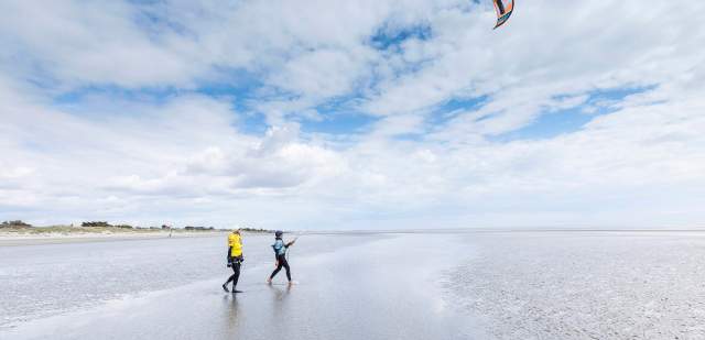 A kitesurfer preparing to enter the water on the beach in Sussex