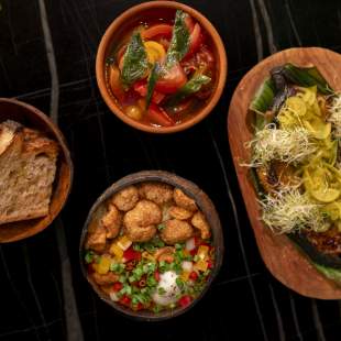 A vibrant platter of Panamanian dishes, featuring a hearty stew, a flavorful fish dish, a rich grain bowl, and crusty bread.