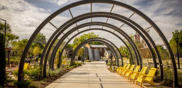 Archways in park with yellow chairs on path
