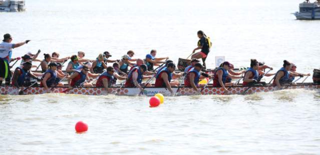 People on dragon boats for race on lake.