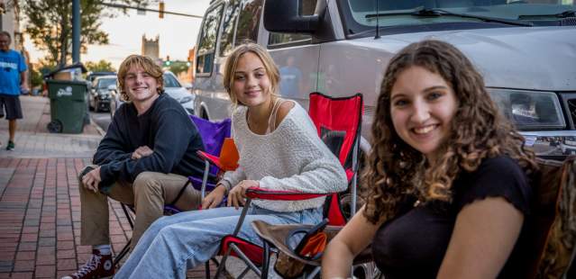 Teens sitting in chairs on sidewalk