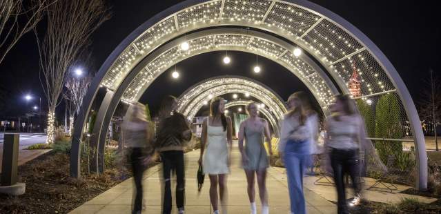 Teens walking under lit arches in park