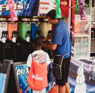 A man serves a young black boy a slushie from his vendor tent at Fayetteville, NC's Dogwood Fall Festival