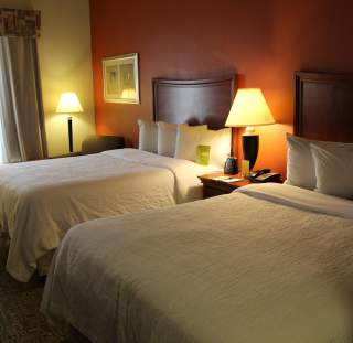 Cozy hotel room in Fayetteville, North Carolina with two neatly made double beds, soft lighting, and a comfortable seating area.