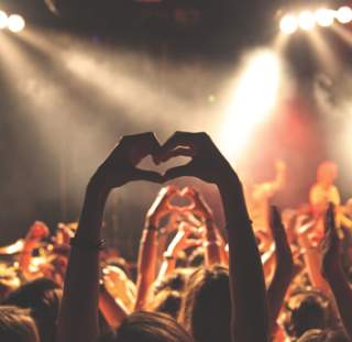 Attendees enjoying a concert in Fayetteville NC, hands up in air forming a heart, showing performers on-stage how they feel about the performance