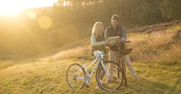 Cannock Chase heathland Autumn sunshine couple on bikes stopping to read map
