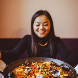 woman with a skillet of seafood