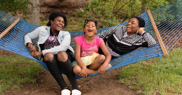 three girls swinging and laughing in a hammock