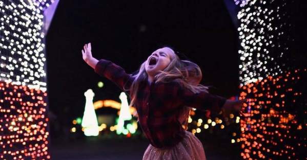 girl jumping under Christmas lights