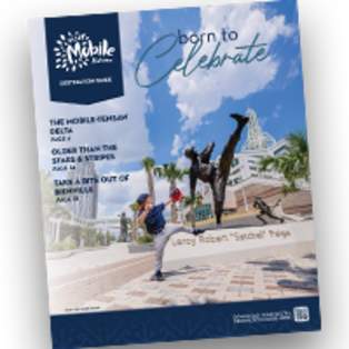 Cover of the 2026 Destination Guide - a boy posing like he is throwing a baseball in front of a statue of Satchel Paige