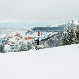 Snowboarding at Brian Head Resort with beautiful red rock in the background.