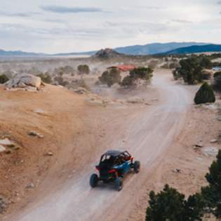 Off road vehicle driving on dusty desert trail with scenic mountains and rugged terrain near Cedar City and Brian Head