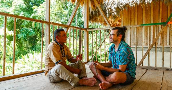 Naso Tjër Di man Interacting with a tourist inside a rural house in the community.