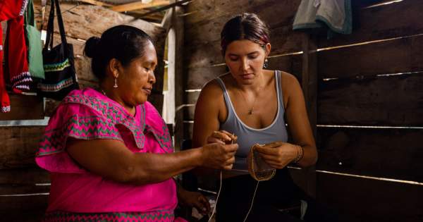 Ngäbe woman wearing  Nagua (traditional dress) hows visitor the weaving of a craft.
