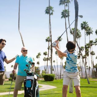 Two men and kid golfing with palm tree background