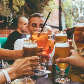 drinks are raised to center in a toast at a dinner table