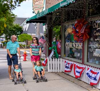 couple pushing two strollers down a downtown sidewalk