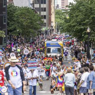 people walking down the street in celebration of the Pride Parde. featuring the mobile VIC.