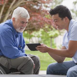 Two men looking at a tablet, one is in a wheelchair