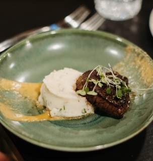Green plate with filet steak and mashed potatoes.