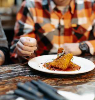 Close up image of restaurant entree with male wearing a plaid shirt in the background.