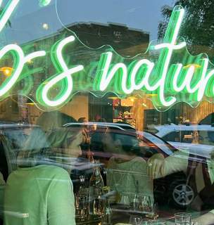 Neon bb's natural sign with people drinking wine on the other side of the glass in rapid city, south dakota