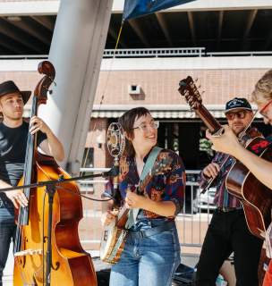 Four person band playing outdoors looking cheerful