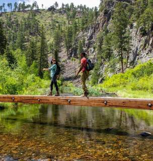 Two hikers cross a bridge on the spring creek portion of the centennial trail in south dakota