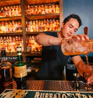 bartender at the windsor block in rapid city pouring a drink with bottles in the background