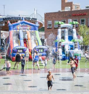 Children running through fountains with bouncy slides in the background