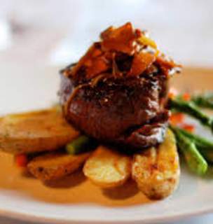 Entree of steak and potatoes with asparagus on white plate.