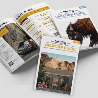 Black Hills & Badlands Vacation Guide with the summer cover, the winter cover, and opened to a page