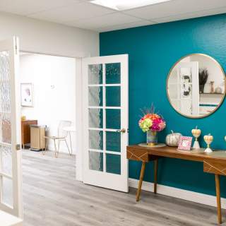 A turquoise wall and accent table lead to open glass doors leading to another event room