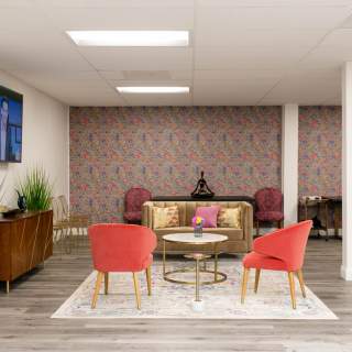 An luxurious sitting space with a floral wallpaper accent wall and a TV screen with all hookup capabilities