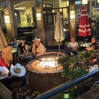 People seated around a fire pit in a restaurant courtyard at night