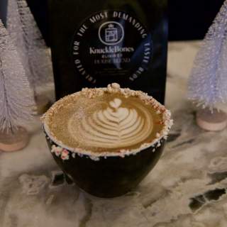 Coffee in mug next to mini artificial Christmas trees