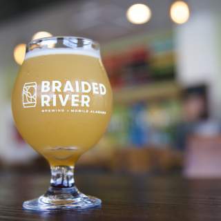 A glass of beer from Braided River Brewing Co sitting on a table