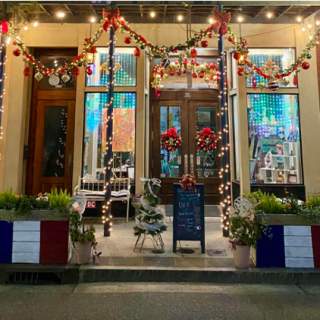 A historic building storefront with Christmas lights and French flags flying