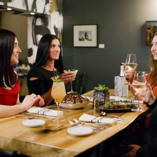4 women sit at a restaurant table dining on gourmet food