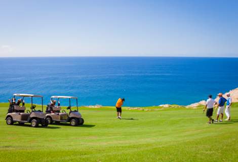 fotografía de personas jugando en un campo de golf con vista al mar