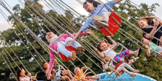 Children riding on a swing ride at Bristol International Balloon Fiesta - Credit Paul Box
