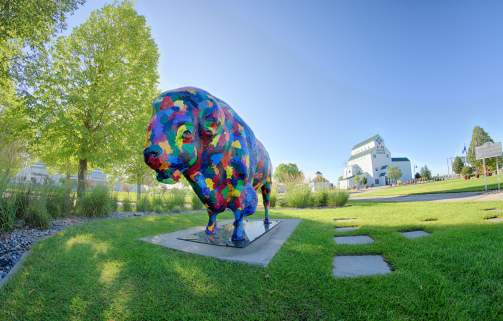 colorful buffalo statue in front of white grain elevator-type building