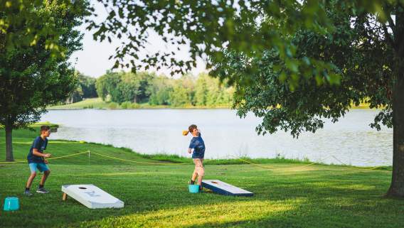 A boy is throwing a cornhole bag while playing cornhole at the Lawn Party at Freeman Lake in Elizabethtown, Kentucky