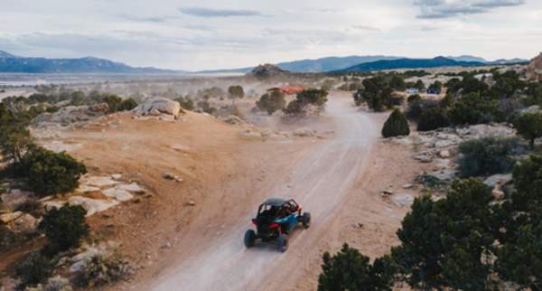 Off road vehicle driving on dusty desert trail with scenic mountains and rugged terrain near Cedar City and Brian Head