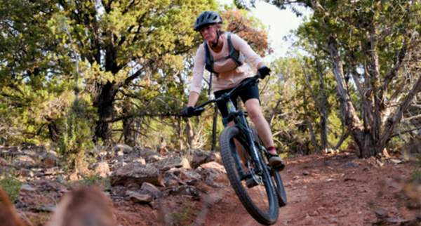 Mountain biker riding through wooded trail with rocky terrain and scenic landscape near Cedar City and Brian Head